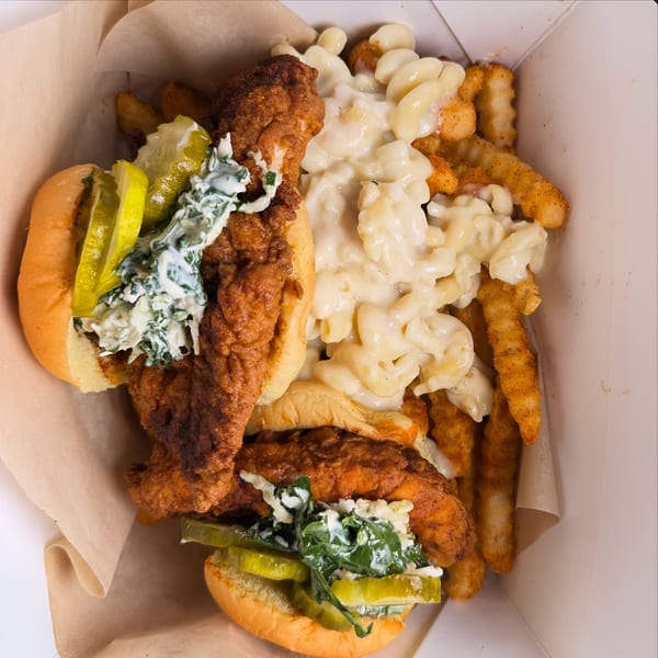 Two Mr Feast Hot Chicken sandwiches with pickles, slaw, mac and cheese, and fries in a box.